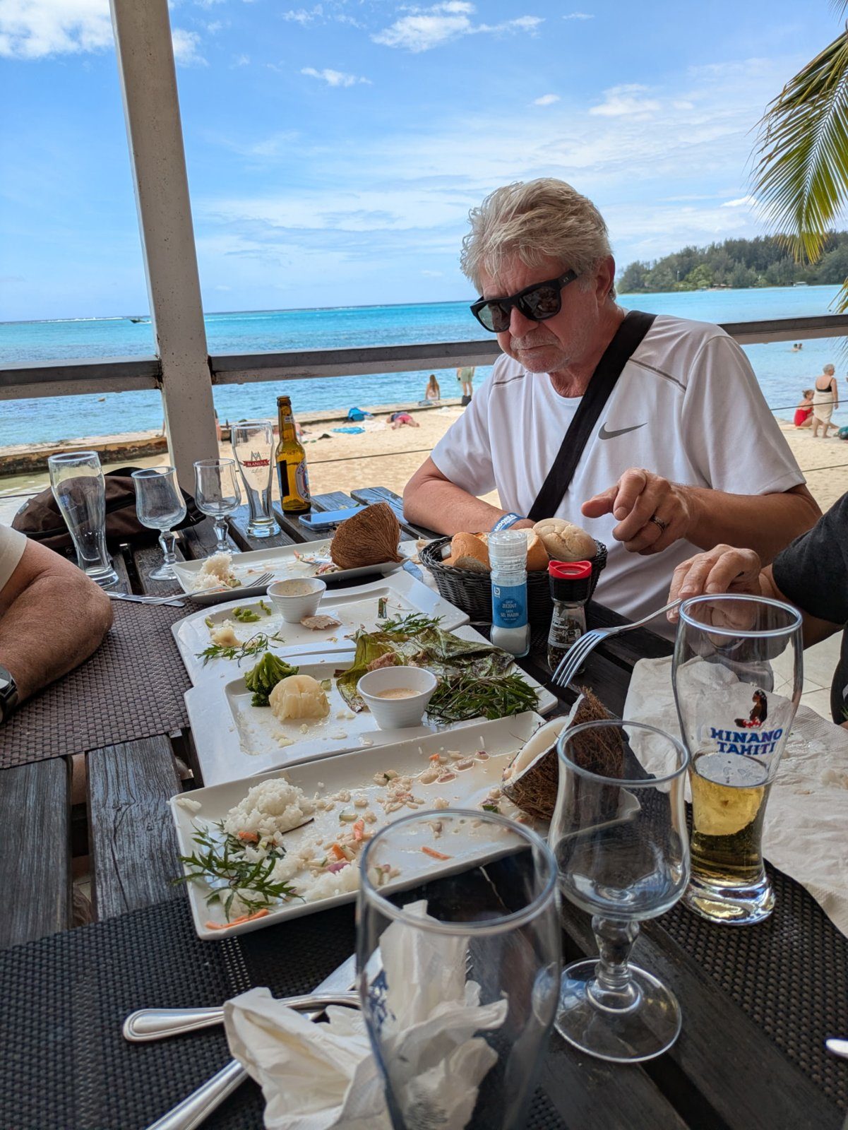 Alex at a beachside lunch table with a glass of Hinano beer